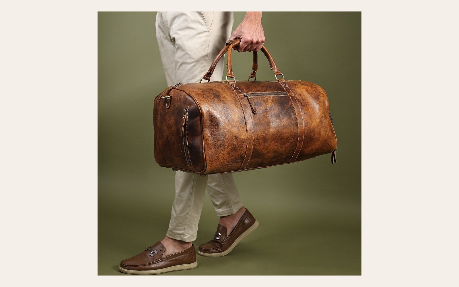 Brown leather duffel carried by hand